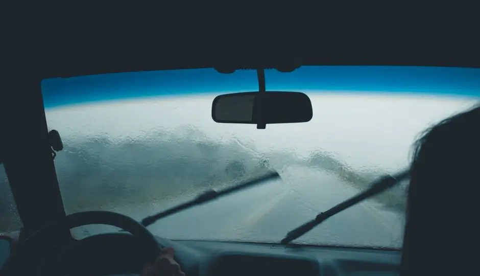 Route mouillée vue depuis le pare-brise sous une pluie fine