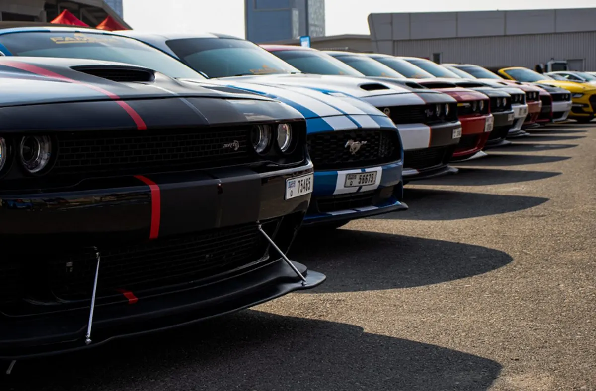Clés de voiture posées sur un capot devant une rangée de véhicules d'occasion