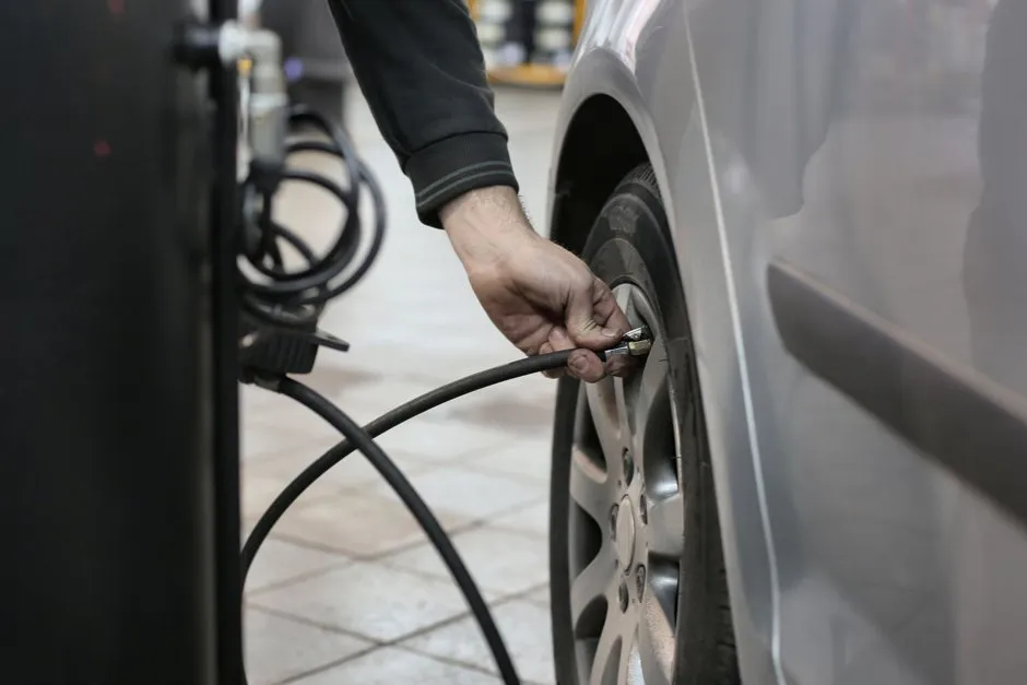 Gonfleur pneu voiture portable avec manomètre numérique posé près d'une roue