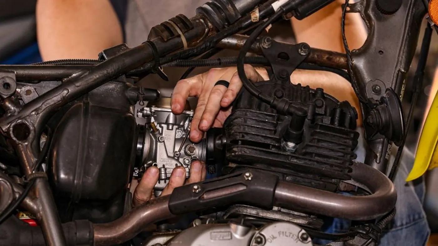 Mécanicien qui resserre une pièce sur une moto dans un atelier propre