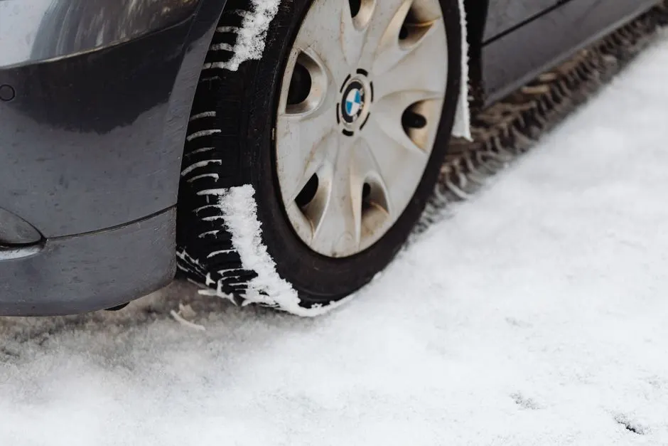 Pneu hiver posé contre une roue sur un sol enneigé