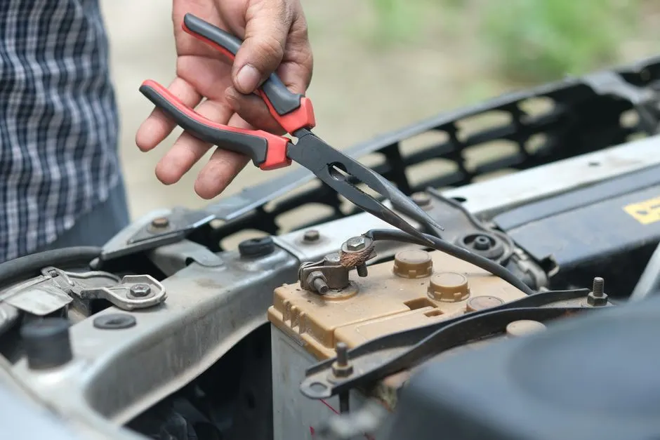 Multimètre posé sur une batterie 12 V dans un compartiment moteur