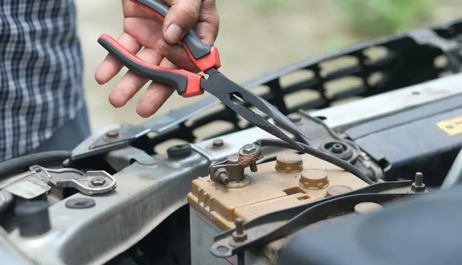 Multimètre posé sur une batterie 12 V dans un compartiment moteur